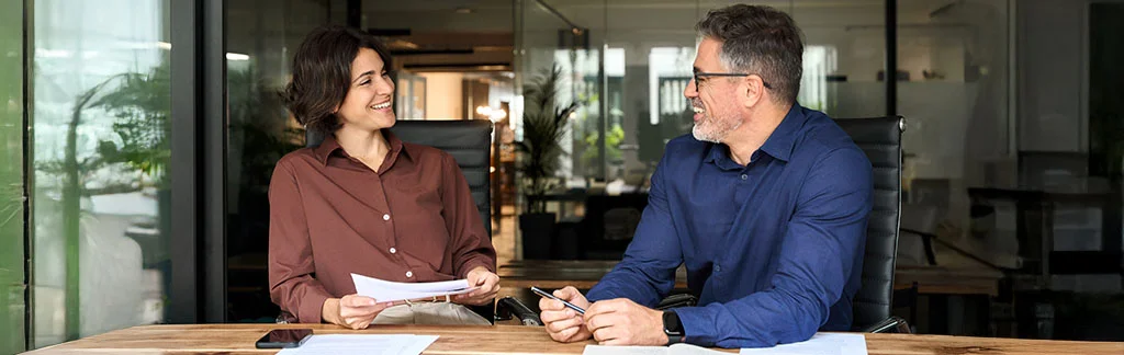 Un conseiller immobilier discutant d'un projet avec une cliente, assis à une table